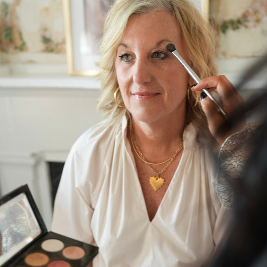 Woman getting makeup applied with a brush in a room setting
