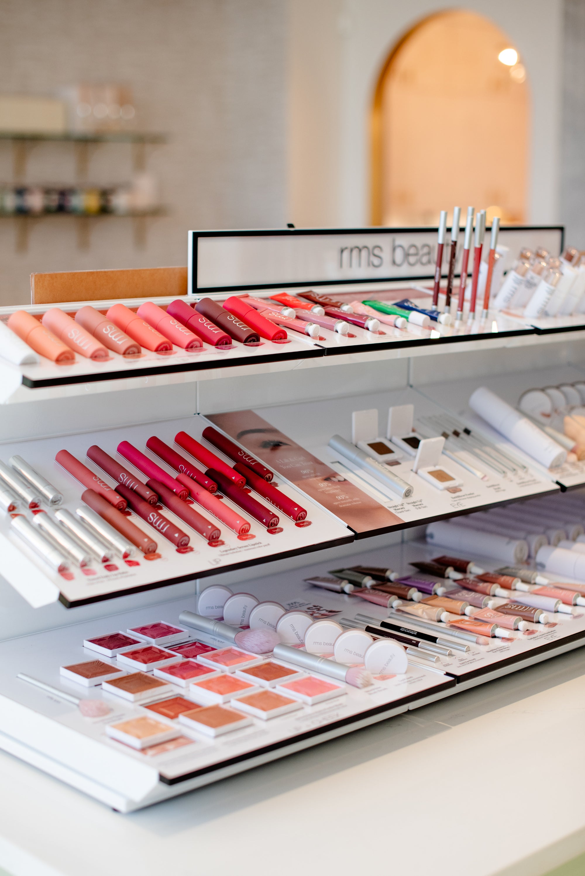 Makeup products including lipsticks and palettes on a display table.